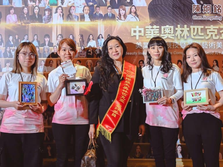 幸妍國際美學苑師生團隊參加美業競賽，多位學員手持創意美甲彩繪作品框與評審長楊嘉欣老師合影，展示競賽級技術。